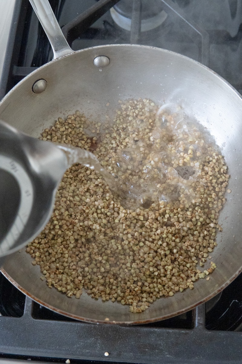 Pouring boiling water into a pan of toasted kasha.