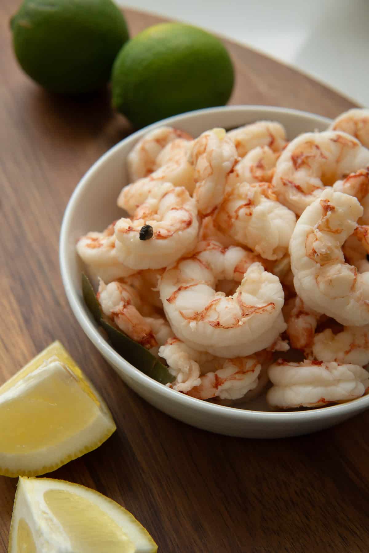 wooden board with limes, lemon wedges and a small bowl of boiled shrimp