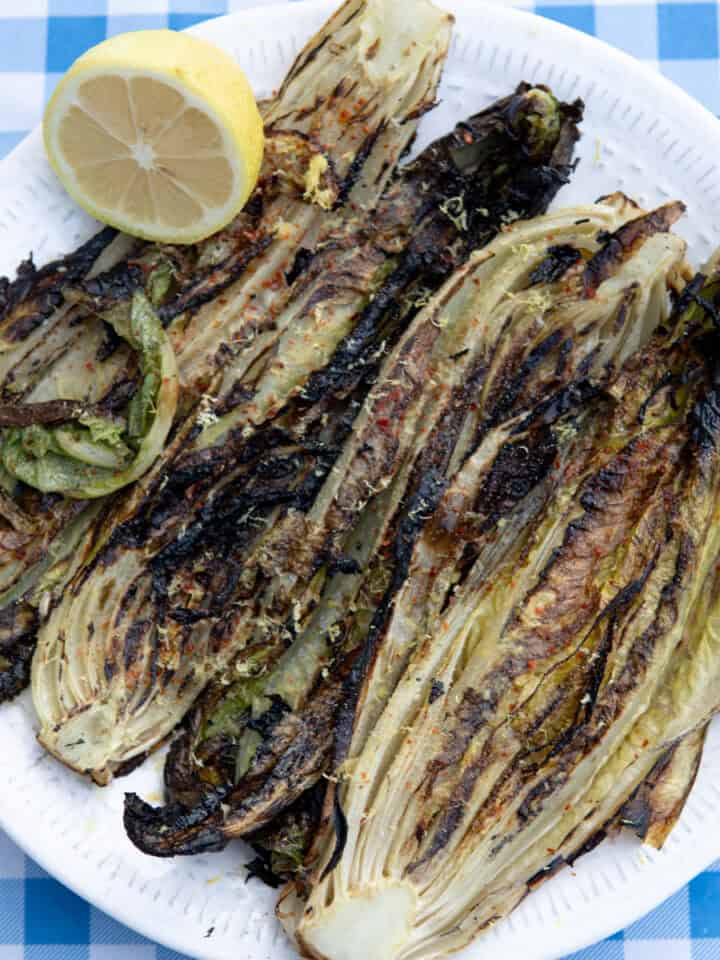 grilled romaine lettuce on a plate with lemon and spices